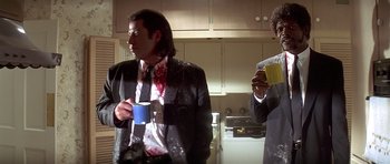 Movie still from “Pulp Fiction” (1994), directed by Quentin Tarantino – A man in a suit and tie holding a coffee cup; Medium shot, Low angle
