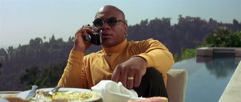Movie still from “Pulp Fiction” (1994), directed by Quentin Tarantino – A man sitting at a table talking on a cell phone; Medium shot, Low angle