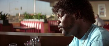 Movie still from “Pulp Fiction” (1994), directed by Quentin Tarantino – A person sitting at a table; Close Up shot, Over the shoulder angle