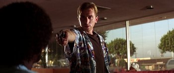Movie still from “Pulp Fiction” (1994), directed by Quentin Tarantino – A man holding a gun while wearing a hawaiian shirt; Close Up shot, Low angle