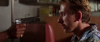 Movie still from “Pulp Fiction” (1994), directed by Quentin Tarantino – A person holding a gun; Close Up shot, Low angle