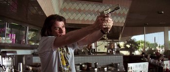 Movie still from “Pulp Fiction” (1994), directed by Quentin Tarantino – A person holding a gun in a kitchen; Medium shot, Low angle