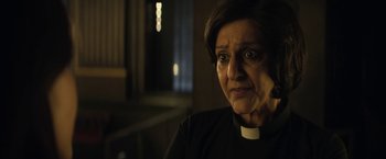 Movie still from “The Sandman” (2022), created by Neil Gaiman – An older woman wearing a priest's collar; Close Up shot, Over the shoulder angle