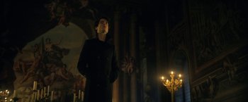 Movie still from “The Sandman” (2022), created by Neil Gaiman – A man standing in a dark room with candles; Medium shot, Low angle