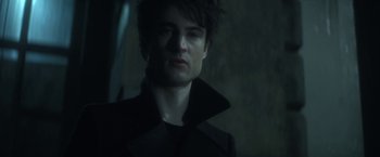 Movie still from “The Sandman” (2022), created by Neil Gaiman – A person wearing a black jacket; Close Up shot, Over the shoulder angle