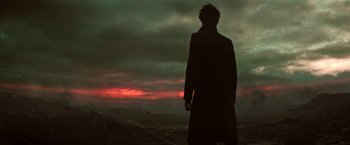 Movie still from “The Sandman” (2022), created by Neil Gaiman – A man standing in front of a cloudy sky at sunset; Medium shot, Low angle
