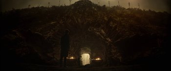 Movie still from “The Sandman” (2022), created by Neil Gaiman – A man standing in front of a cave with candles; Extreme Wide shot, Low angle