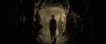 Movie still from “The Sandman” (2022), created by Neil Gaiman – A person is standing in a cave looking into the distance; Wide shot, Low angle