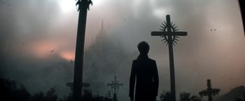 Movie still from “The Sandman” (2022), created by Neil Gaiman – A man standing in front of a cross and a castle; Wide shot, Low angle