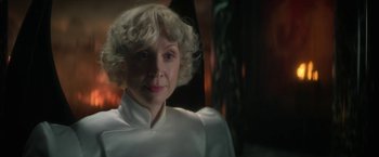 Movie still from “The Sandman” (2022), created by Neil Gaiman – An older woman in a white dress is looking at the camera; Close Up shot, Over the shoulder angle