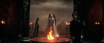 Movie still from “The Sandman” (2022), created by Neil Gaiman – An image of an angel in front of a fire pit; Wide shot, Over the shoulder angle