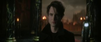 Movie still from “The Sandman” (2022), created by Neil Gaiman – A young man with dark hair is looking at the camera; Close Up shot, Over the shoulder angle