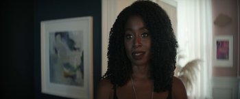 Movie still from “The Sandman” (2022), created by Neil Gaiman – A person wearing a necklace with a picture in the background; Close Up shot, Over the shoulder angle