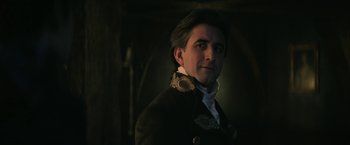 Movie still from “The Sandman” (2022), created by Neil Gaiman – A person wearing a suit; Close Up shot, Low angle