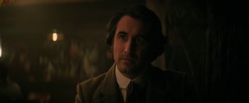 Movie still from “The Sandman” (2022), created by Neil Gaiman – A person wearing a suit and tie; Close Up shot, Over the shoulder angle