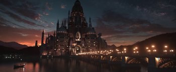 Movie still from “The Sandman” (2022), created by Neil Gaiman – A night view of a large building with lights on it; Extreme Wide shot, Low angle