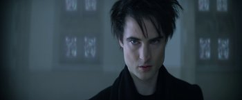 Movie still from “The Sandman” (2022), created by Neil Gaiman – A person wearing a black shirt; Close Up shot, Over the shoulder angle