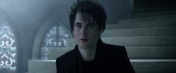 Movie still from “The Sandman” (2022), created by Neil Gaiman – A man with a black shirt and a black jacket; Close Up shot, Over the shoulder angle
