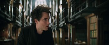 Movie still from “The Sandman” (2022), created by Neil Gaiman – A young man is looking into the distance in a library; Close Up shot, Low angle