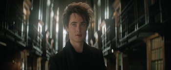 Movie still from “The Sandman” (2022), created by Neil Gaiman – A young man with spiky brown hair and a black jacket; Close Up shot, Low angle