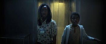 Movie still from “The Sandman” (2022), created by Neil Gaiman – Two women standing in a room with a door in the background; Medium shot, Low angle