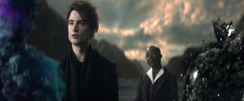 Movie still from “The Sandman” (2022), created by Neil Gaiman – Two people standing in front of a cloudy sky; Medium shot, Over the shoulder angle
