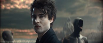 Movie still from “The Sandman” (2022), created by Neil Gaiman – A person wearing a black jacket; Close Up shot, Over the shoulder angle