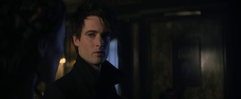 Movie still from “The Sandman” (2022), created by Neil Gaiman – A man with a black shirt is looking at the camera; Close Up shot, Over the shoulder angle