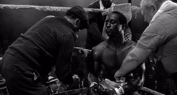 Movie still from “Raging Bull” (1980), directed by Martin Scorsese – An old black and white photo of a man in a boxing ring; Medium shot, Low angle