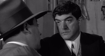 Movie still from “Raging Bull” (1980), directed by Martin Scorsese – A black - and - white photo of a man in a suit and tie looking at another man in a hat; Close Up shot, Over the shoulder angle