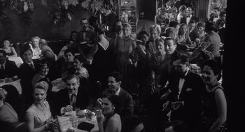 Movie still from “Raging Bull” (1980), directed by Martin Scorsese – A black and white photo of a group of people sitting at a table; Wide shot, High angle