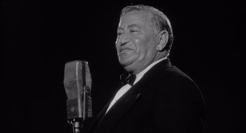 Movie still from “Raging Bull” (1980), directed by Martin Scorsese – An older man in a suit and bow tie holding a microphone; Close Up shot, Low angle