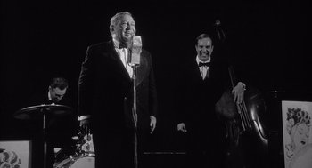 Movie still from “Raging Bull” (1980), directed by Martin Scorsese – A man in a suit and tie standing in front of a microphone; Medium shot, Low angle
