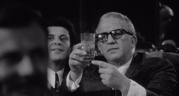 Movie still from “Raging Bull” (1980), directed by Martin Scorsese – A man holding a glass of wine in front of another man in a suit; Close Up shot, Low angle