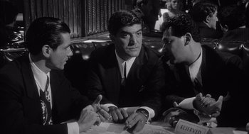 Movie still from “Raging Bull” (1980), directed by Martin Scorsese – A group of men sitting at a table in a restaurant; Medium shot, Over the shoulder angle