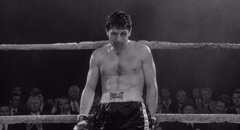 Movie still from “Raging Bull” (1980), directed by Martin Scorsese – A black and white photo of a man standing in a boxing ring; Medium shot, Low angle