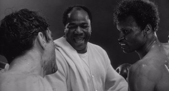 Movie still from “Raging Bull” (1980), directed by Martin Scorsese – A black and white photo of a man laughing with two other men; Close Up shot, Low angle