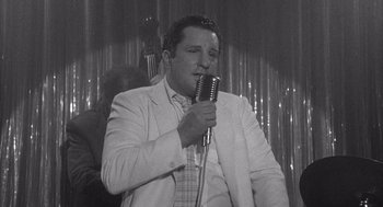 Movie still from “Raging Bull” (1980), directed by Martin Scorsese – A black and white photo of a man holding a microphone; Medium shot, Over the shoulder angle