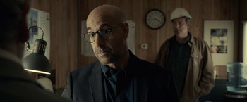 Movie still from “The Silence” (2019), directed by John R. Leonetti – A bald man wearing glasses and a jacket; Close Up shot, Over the shoulder angle