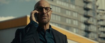 Movie still from “The Silence” (2019), directed by John R. Leonetti – A bald man with glasses is talking on a cell phone; Close Up shot, Low angle