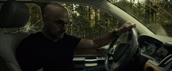 Movie still from “The Silence” (2019), directed by John R. Leonetti – A man driving a car in a forest; Close Up shot, Low angle