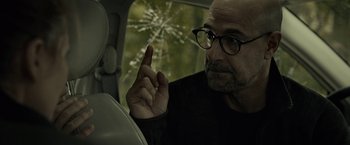Movie still from “The Silence” (2019), directed by John R. Leonetti – A man in a car with his finger up to his eye; Close Up shot, Over the shoulder angle