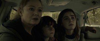 Movie still from “The Silence” (2019), directed by John R. Leonetti – Three people in a car looking at the camera; Close Up shot, Low angle