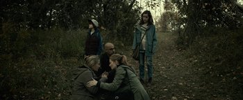 Movie still from “The Silence” (2019), directed by John R. Leonetti – A group of people standing in the woods; Wide shot, High angle