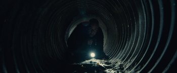 Movie still from “The Silence” (2019), directed by John R. Leonetti – A man with a flashlight is in a tunnel; Medium shot, Low angle