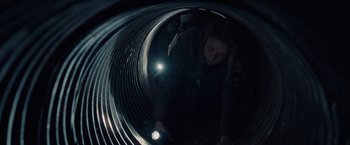 Movie still from “The Silence” (2019), directed by John R. Leonetti – A woman is bending over looking into a tunnel; Medium shot, High angle