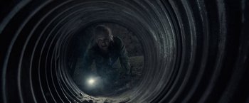 Movie still from “The Silence” (2019), directed by John R. Leonetti – A person in a tunnel with a flashlight; Wide shot, Overhead angle