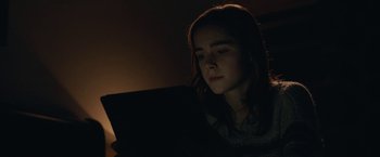 Movie still from “The Silence” (2019), directed by John R. Leonetti – A woman is looking at a laptop in the dark; Close Up shot, Low angle