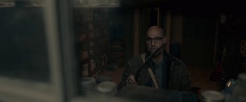 Movie still from “The Silence” (2019), directed by John R. Leonetti – A man with glasses is smoking a cigarette; Medium shot, Over the shoulder angle