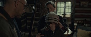 Movie still from “The Silence” (2019), directed by John R. Leonetti – A woman is helping a boy put on a hat; Medium shot, Over the shoulder angle